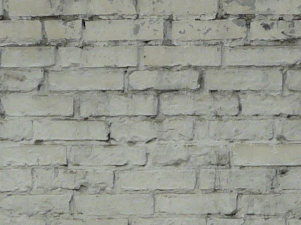 Brick fence texture made up of bricks painted white, with two tall columns made up of similar bricks. Bricks are in various degrees of relief and states of erosion.